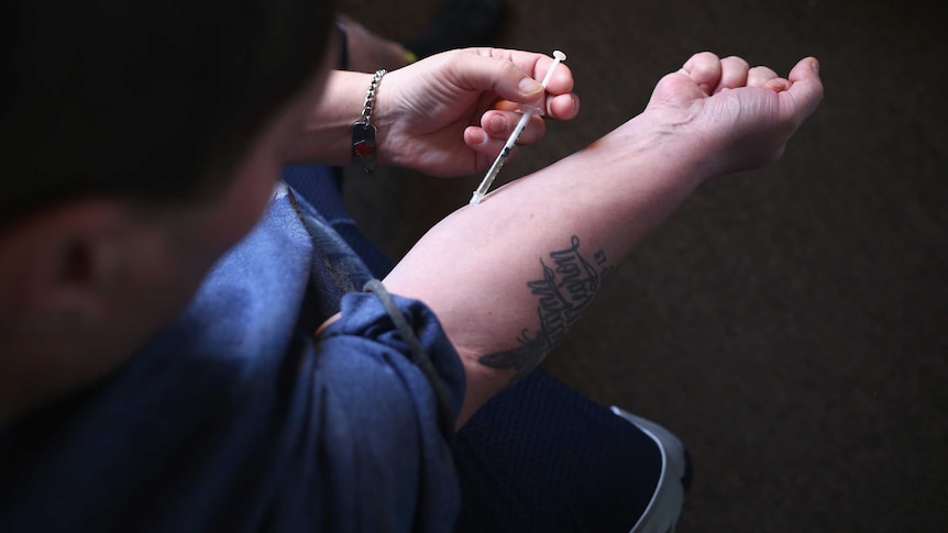A heroin user injects himself