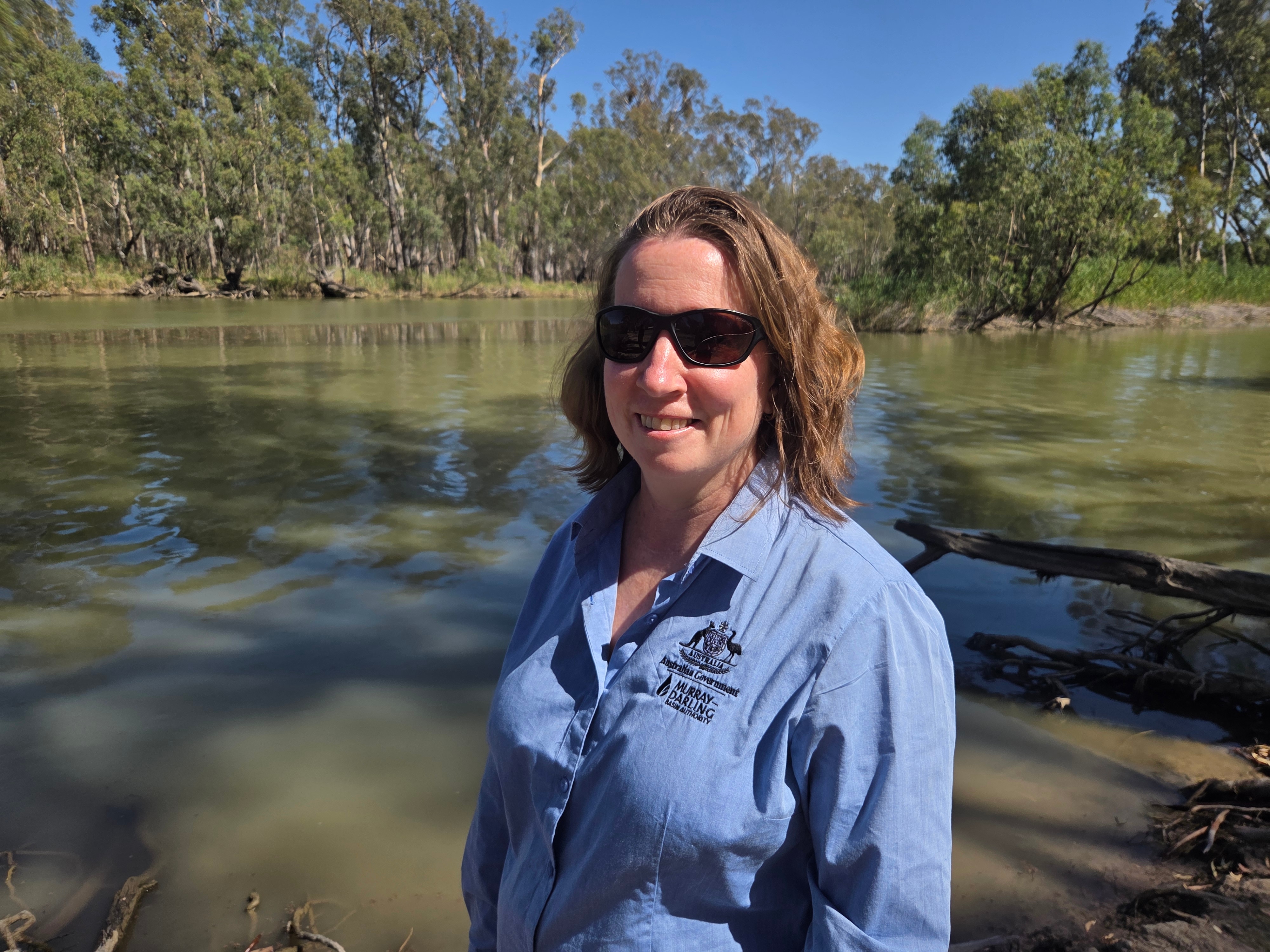 Natalie stands by the river and smiles at the camera