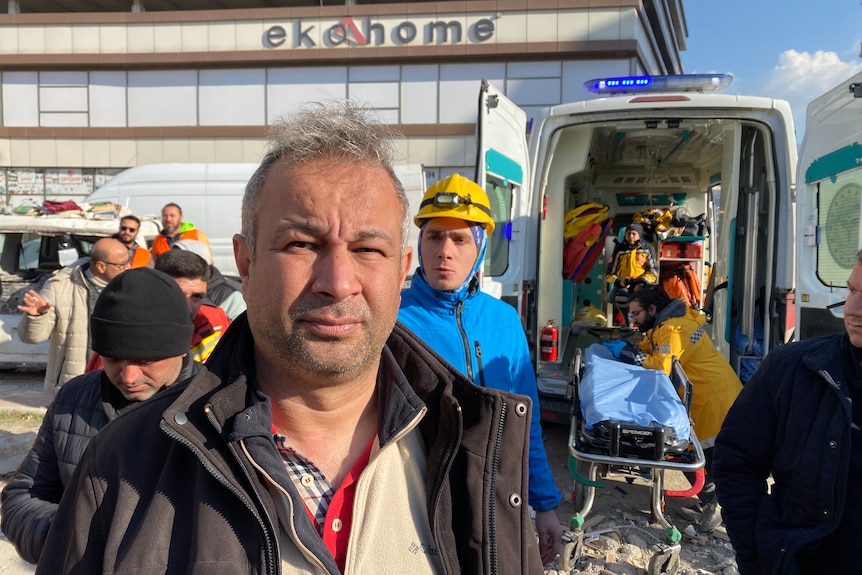 A man stands next to an open ambulance 