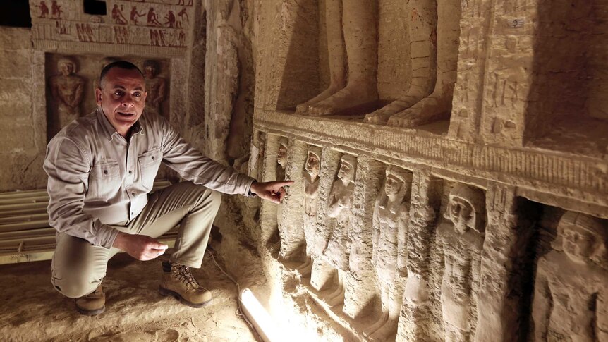 Mostafa Waziri, secretary general of the Supreme Council of Antiquities, crouches down and points out statues at the tomb.