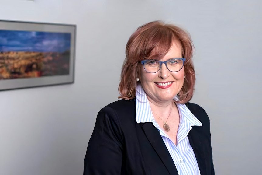 La professeure adjointe Karen Price, présidente du RACGP, sourit à l'appareil photo avec une photo de paysage en arrière-plan