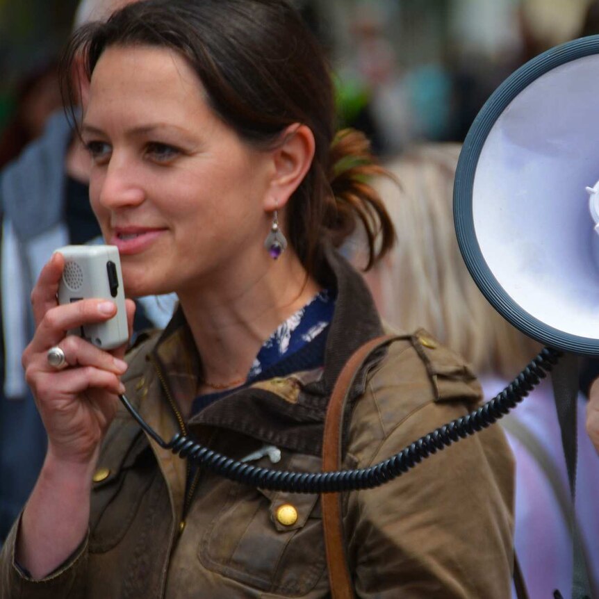 a woman stands at a protest with a megaphone