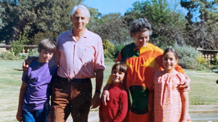 a 1960s colour photo of a couple and their children on a large lawn in front of a fountain