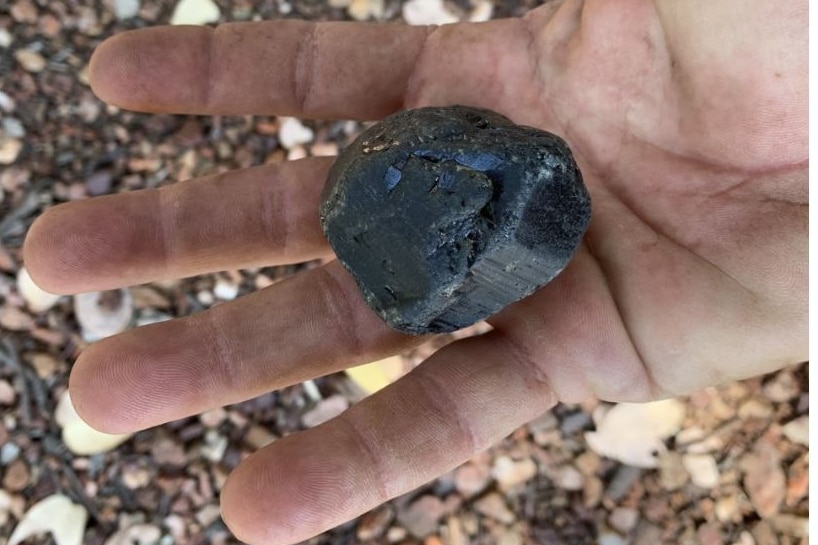 A hand holding a large sapphire