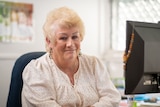 Photo of an older woman with dyed blonde hair and a knowing smile