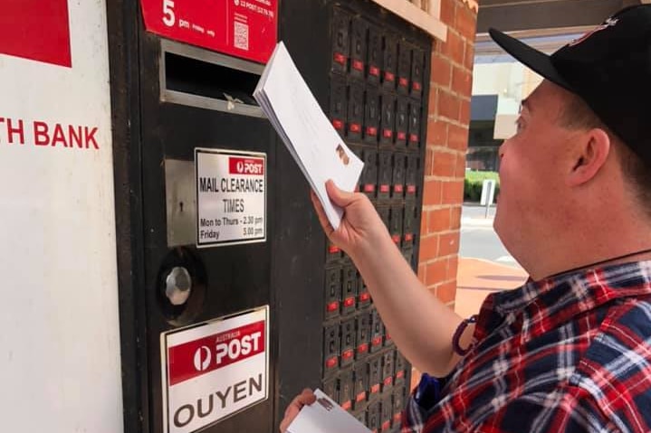 A man putting letters into a post box.