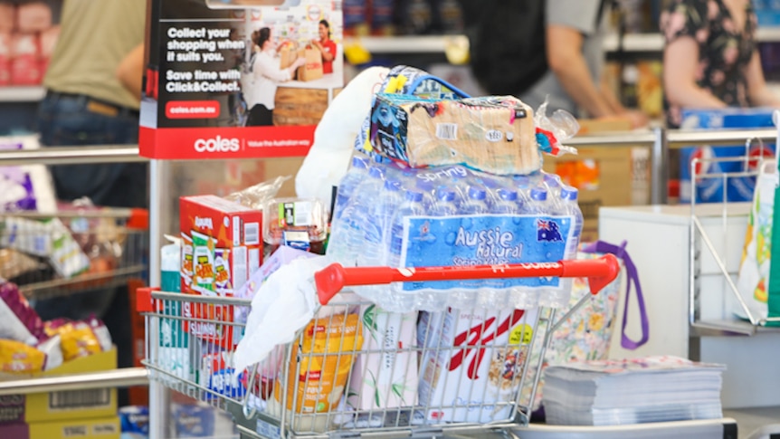 A shopping trolley full with bottled water, cereals and other essentials.