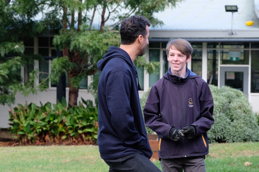 Harper and Daniel look at each other as they chat in the school yard.