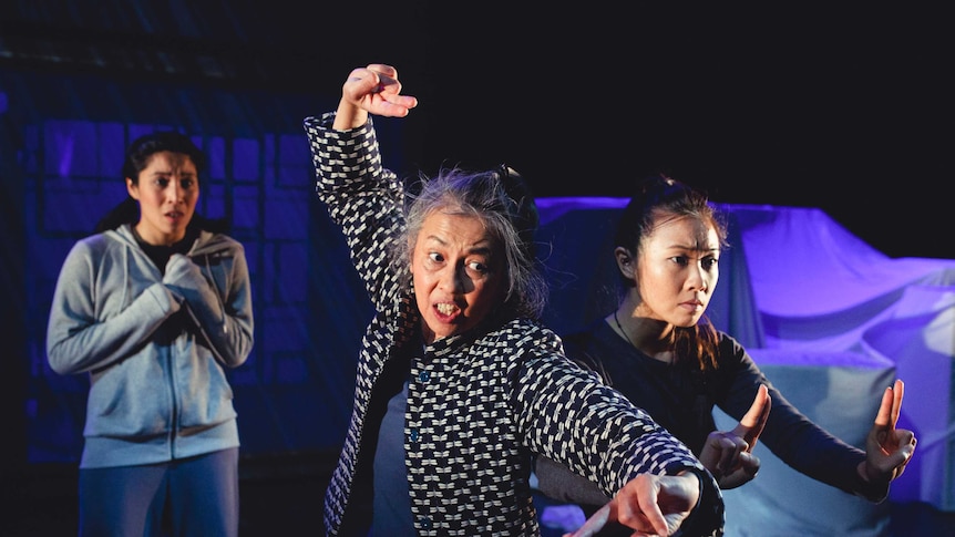 Three east asian women, a young woman scared in the back and an older woman and another young woman striking fighting poses