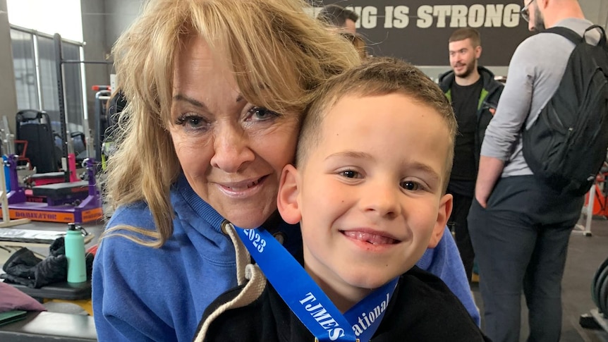 A young boy and his grandmother both with a gold medal around their neck