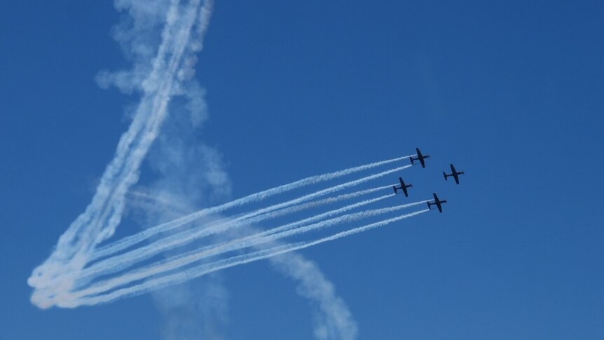 Photo of four RAAF planes flying in the blue sky, leaving white streaks behind