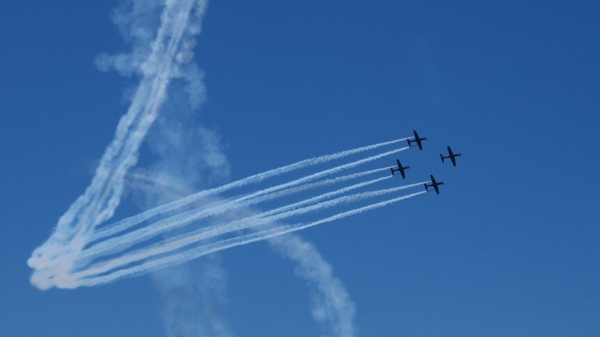 Photo of four RAAF planes flying in the blue sky, leaving white streaks behind