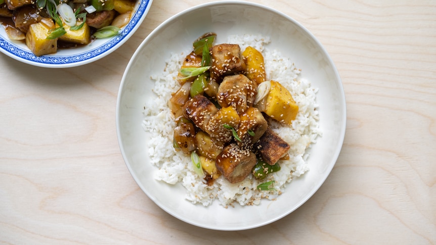 A bowl of white rice topped with sweet and sour eggplant, a vegetarian recipe by Hetty McKinnon.