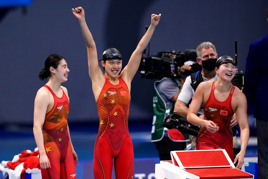 Three women wearing red tops and smiling