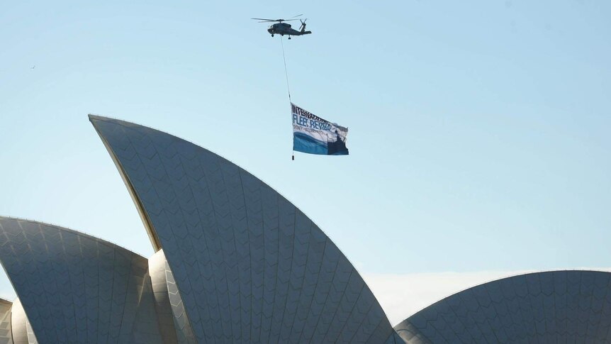 A Royal Australian Navy helicopter flies over the Sydney Opera House during the International Fleet Review.