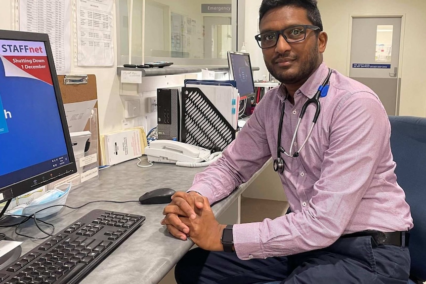 Man sitting at a desk, stethoscope around his neck.