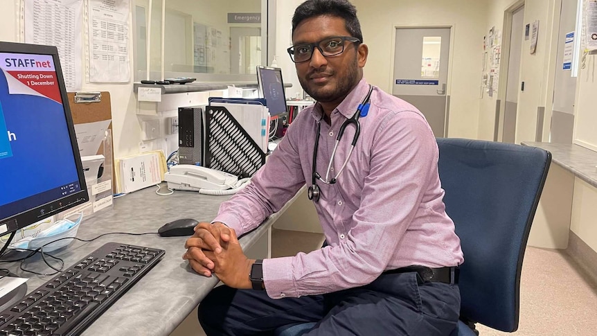 Man sitting at a desk, stethoscope around his neck.