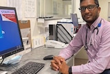 Man sitting at a desk, stethoscope around his neck.