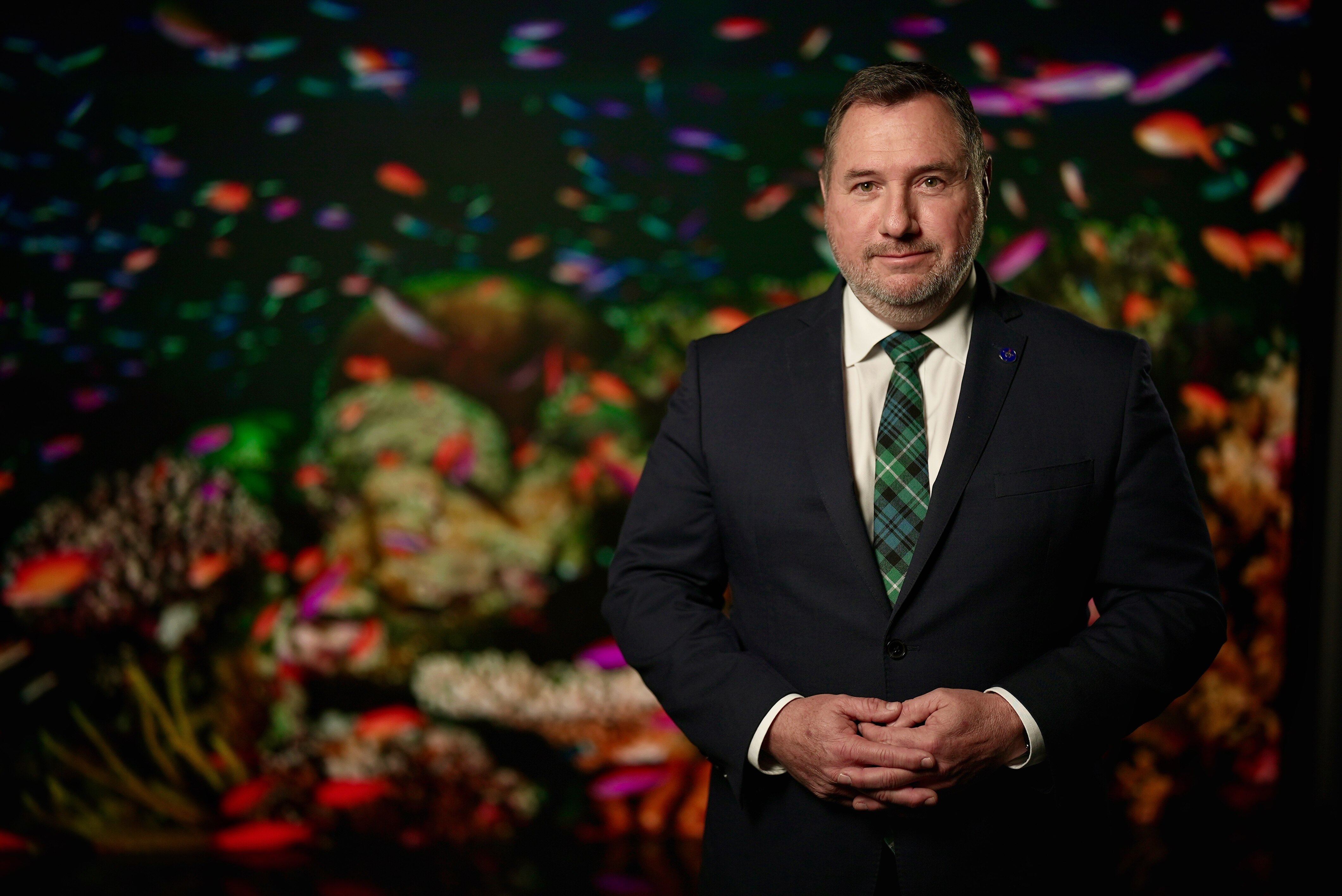 a man in a suit and tie in front of a fish photo