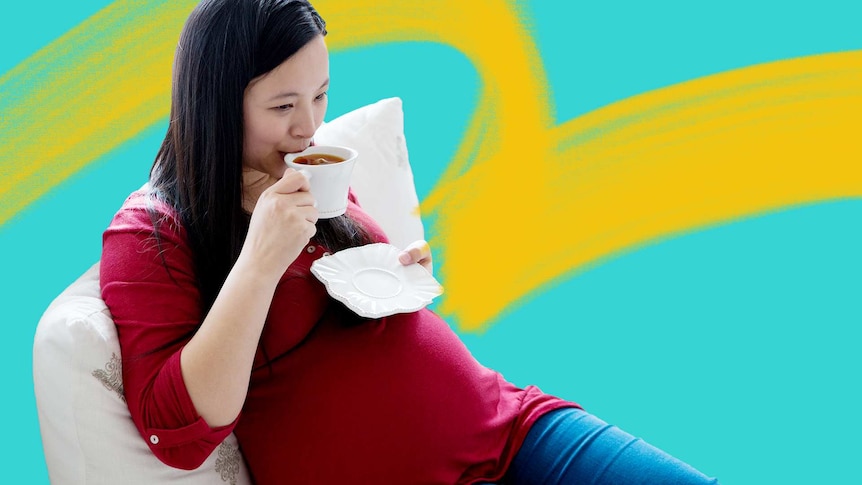 Young pregnant woman sips a coffee while seated on the lounge.