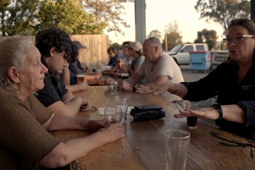 Locals chatting around a table in an outdoor area at the Willawarrin Pub