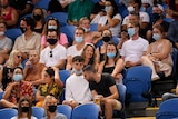 A group of tennis fans sit in the crowd at Melbourne Park for an Australian Open match.