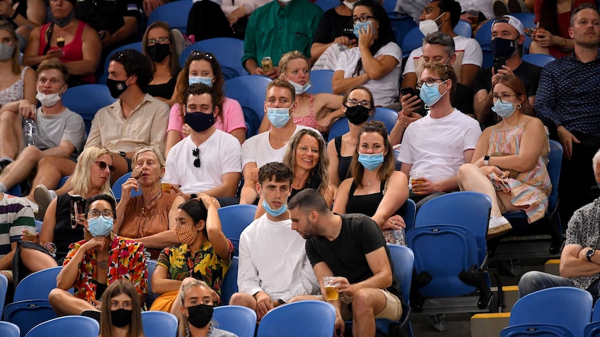 A group of tennis fans sit in the crowd at Melbourne Park for an Australian Open match.