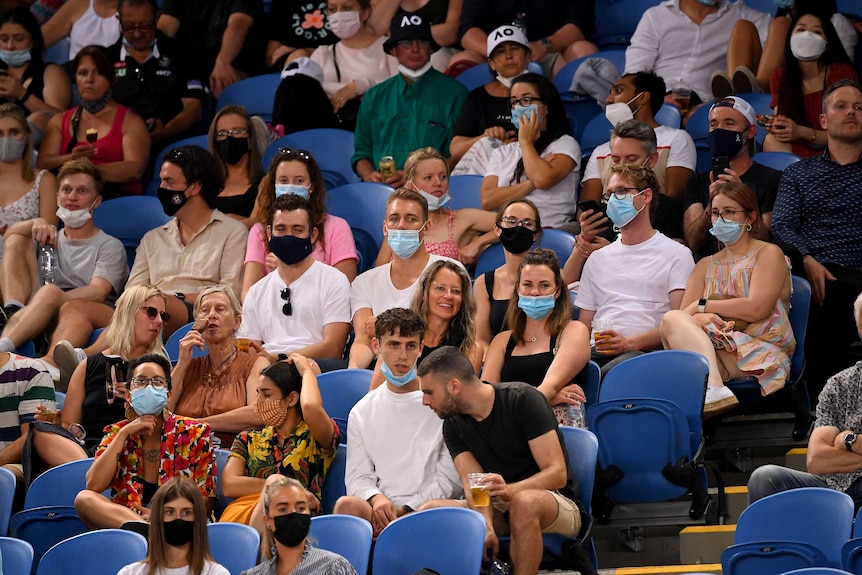 A group of tennis fans sit in the crowd at Melbourne Park for an Australian Open match.
