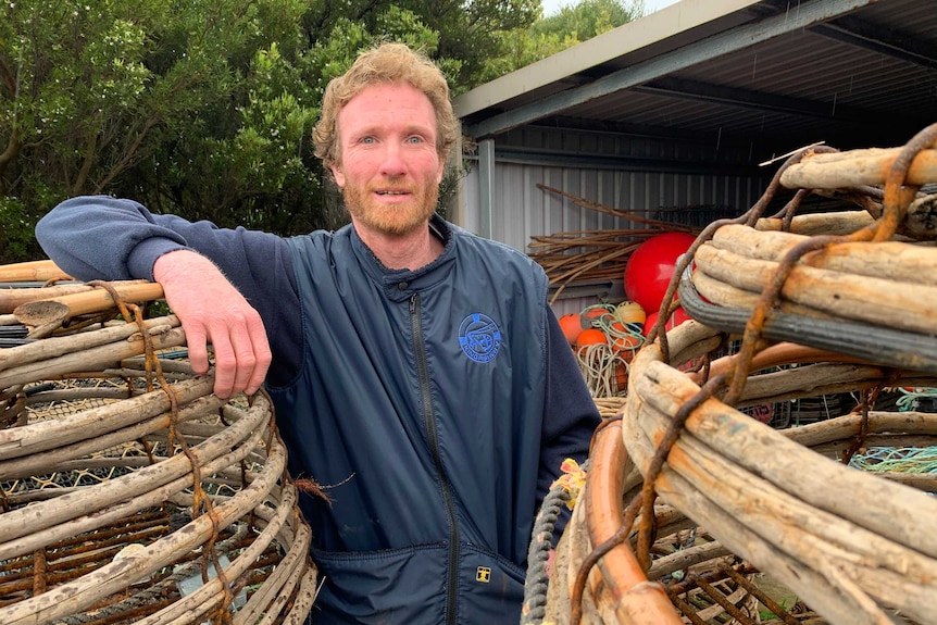 A man standing between lobster traps.