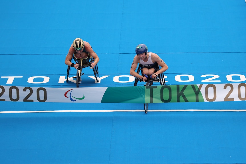An American paralympic triathlete passes her Australian rival as they approach the tape on the finish line.