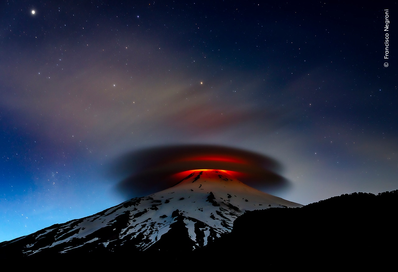 A double lenticular cloud is illuminated at nightfall by the lava emitted from the Villarrica volcano, Chile. 