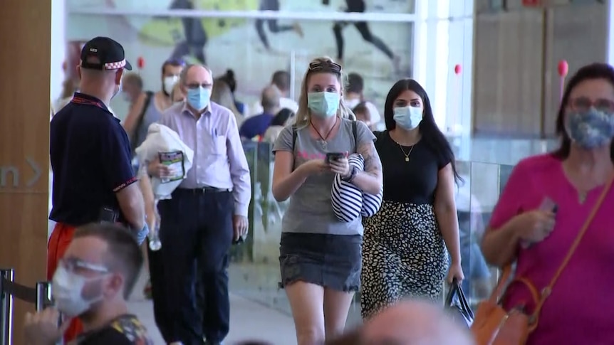 Masked passengers arrive at Adelaide Airport.