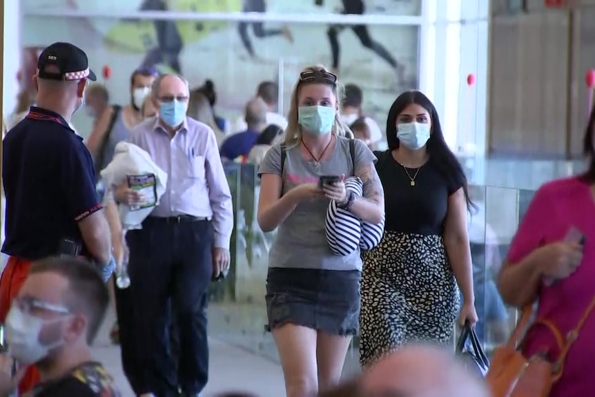 Masked passengers arrive at Adelaide Airport.