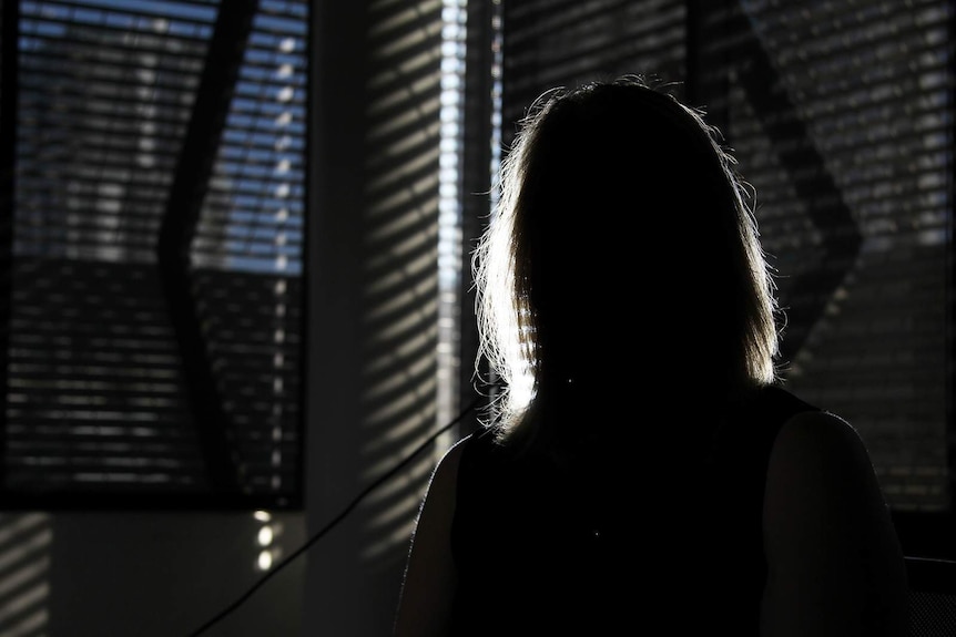 A photo of a woman's silhouette, backlit against an office conference room.