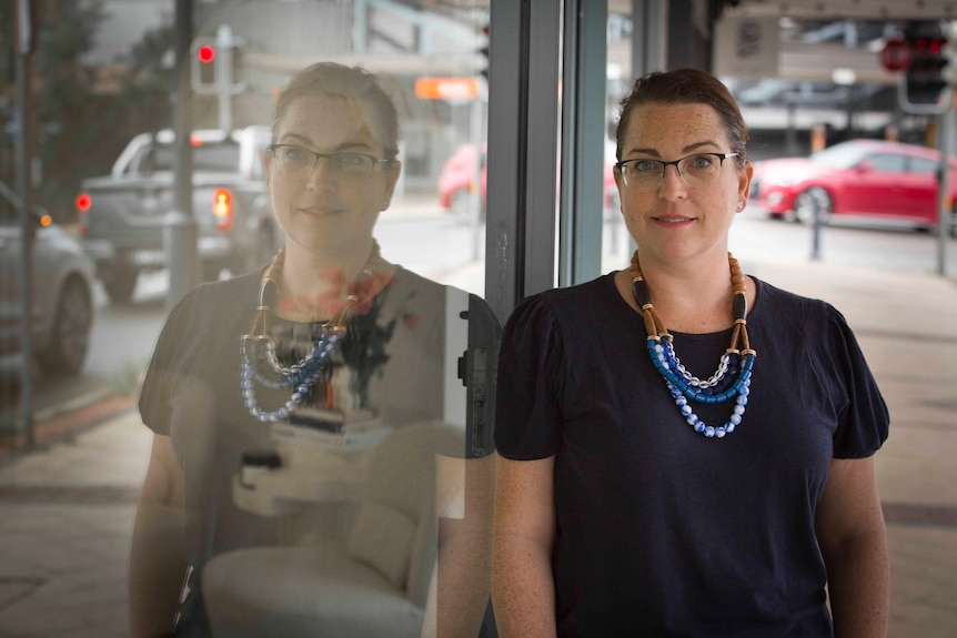 Julia Gilchrist leans against a shop window which reflects her image.