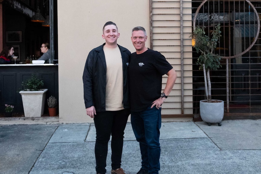 Two men standing outside a building which has the sign Granddad Jack's Craft Distillery.