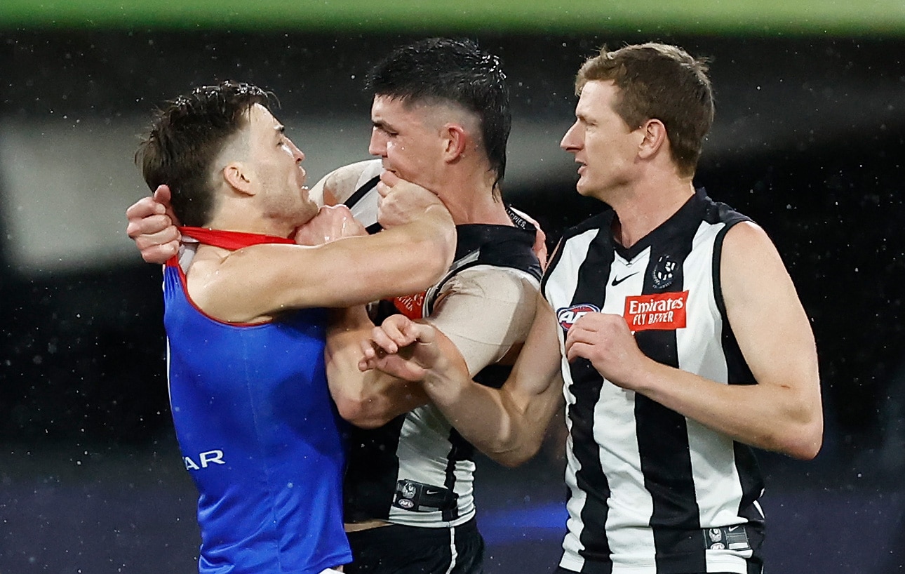 Two AFL players come together in a melee, showing anger with each other.
