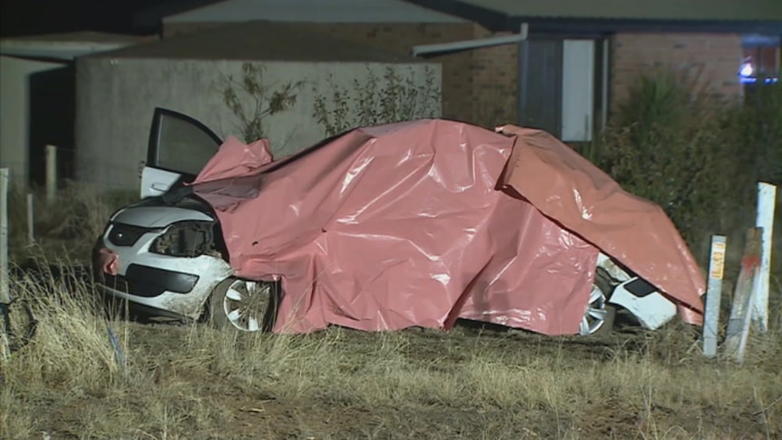 A white car is covered with a tarp after a fatal crash at Navarre in country Victoria.