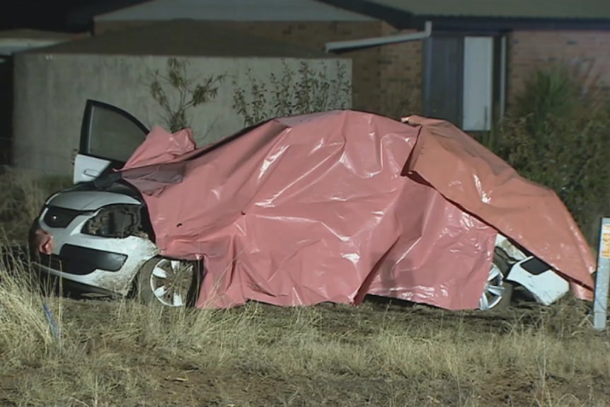 A white car is covered with a tarp after a fatal crash at Navarre in country Victoria.
