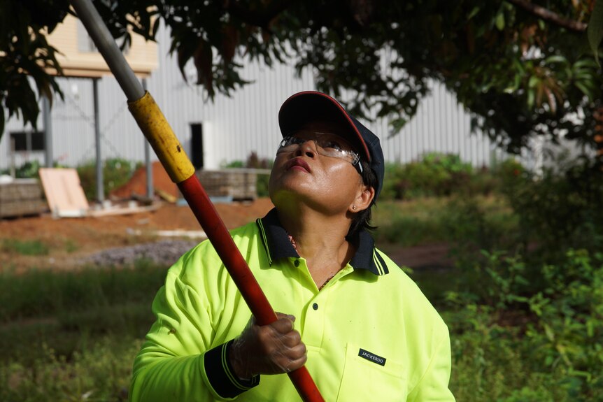Photo of a woman holding a pruning stick.