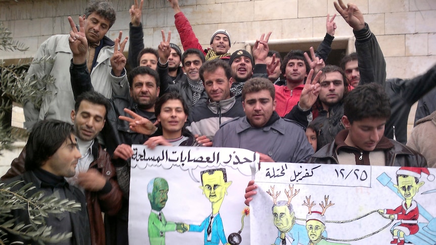 Demonstrators with anti-Assad cartoons