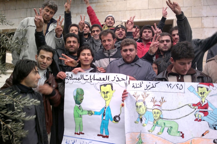 Demonstrators with anti-Assad cartoons