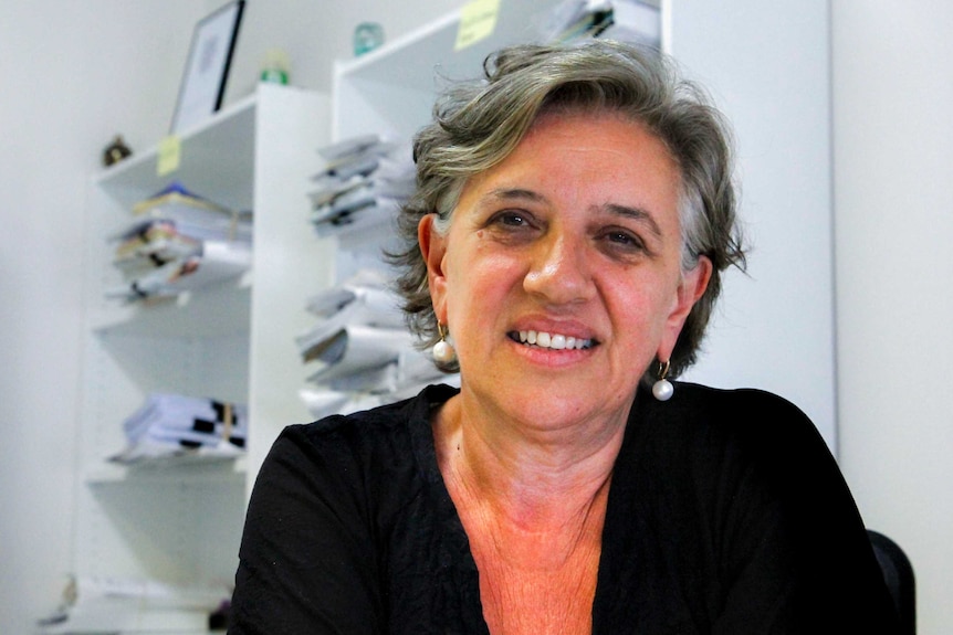 Women sitting stares toward camera, with files in background.