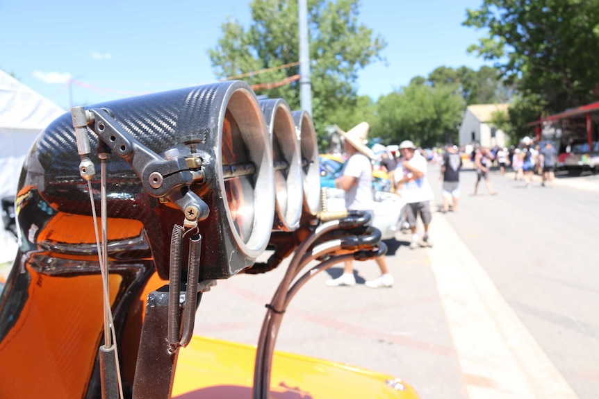 A car engine with Summernats crowds in the background.
