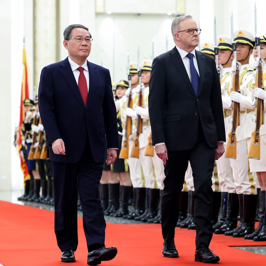 Li Qiang and Anthony Albanese walk down a red carpet in front of ceremonial guards holding guns