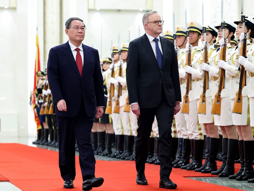 Li Qiang and Anthony Albanese walk down a red carpet in front of ceremonial guards holding guns