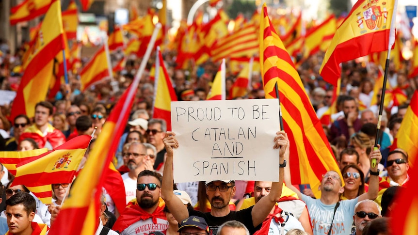 A man holds up a sign reading "proud to be Catalan and Spanish" during a protest in Barcelona