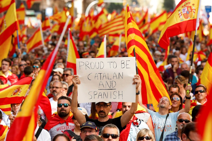 A man holds up a sign reading "proud to be Catalan and Spanish" during a protest in Barcelona