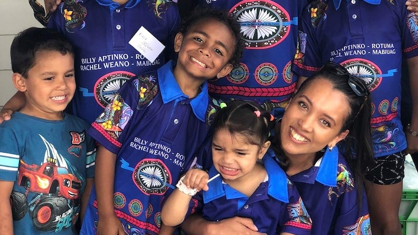 A group of family members from the Torres Straight Islands smile towards the camera