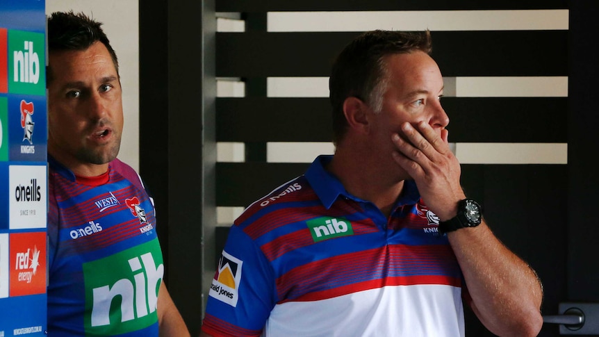 NRL player stares at a camera as he and his coach arrive to face the media as he resigns as captain.